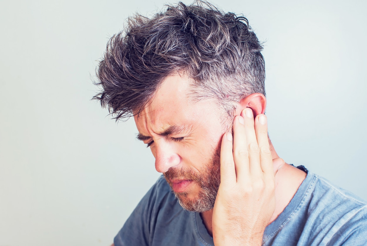 Man with earache is holding his aching ear