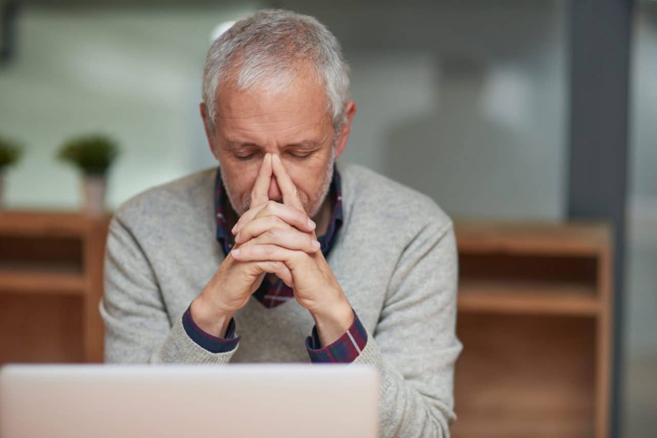 Man putting his fingers on his nose in pain