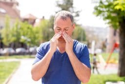 Man with congestion holds his nose