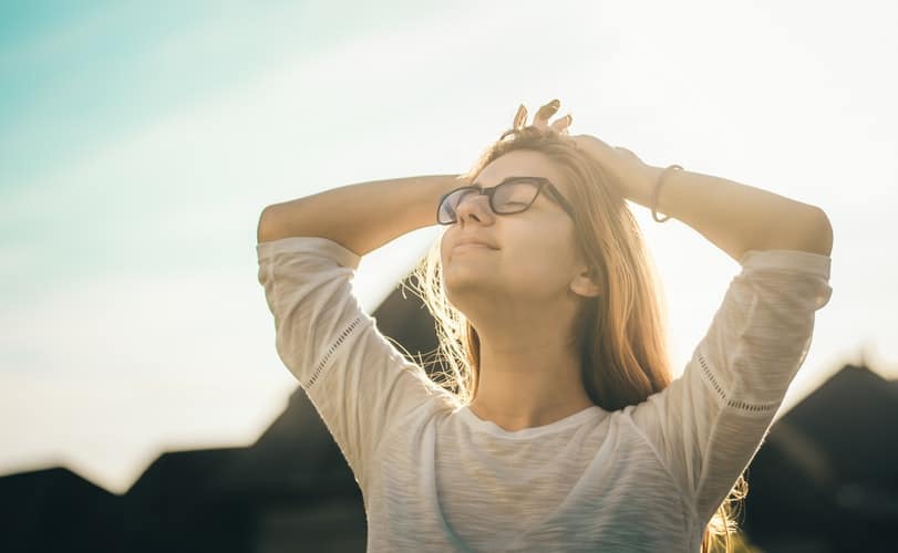 Woman taking deep breath outside.