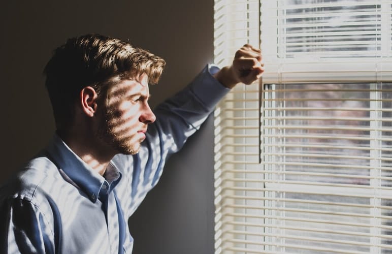 Lonely man looks outside of window.