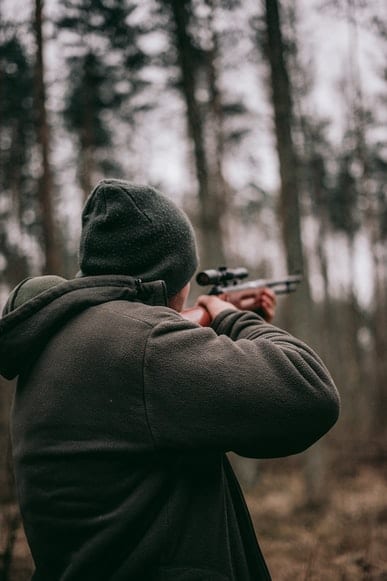 Man hunting with a rifle in a forest.