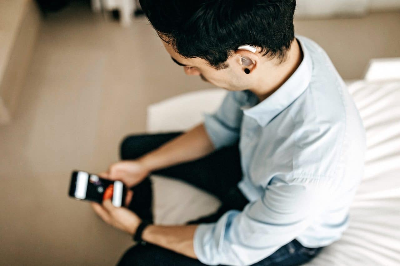 Businessman with hearing aid looking at cellphone.