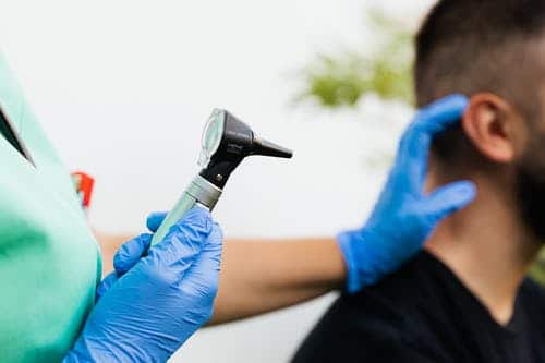 Man getting a hearing exam with an otoscope.