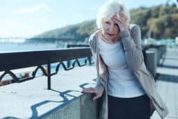 Older woman feeling dizzy while out on a walk.