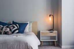 Nightstand with a small lamp next to a bed.