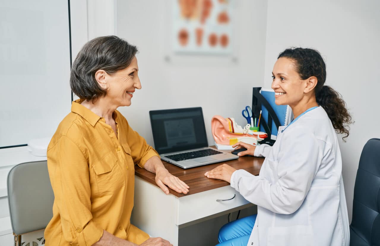 Woman discussing hearing aid options with her audiologist.