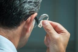 Man inserts hearing aid in his ear
