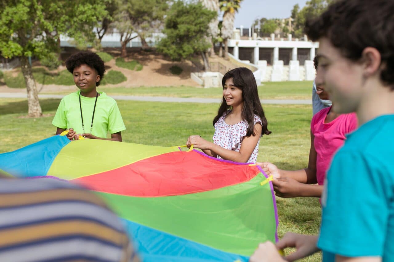 Children outdoors holding a parachute tent.