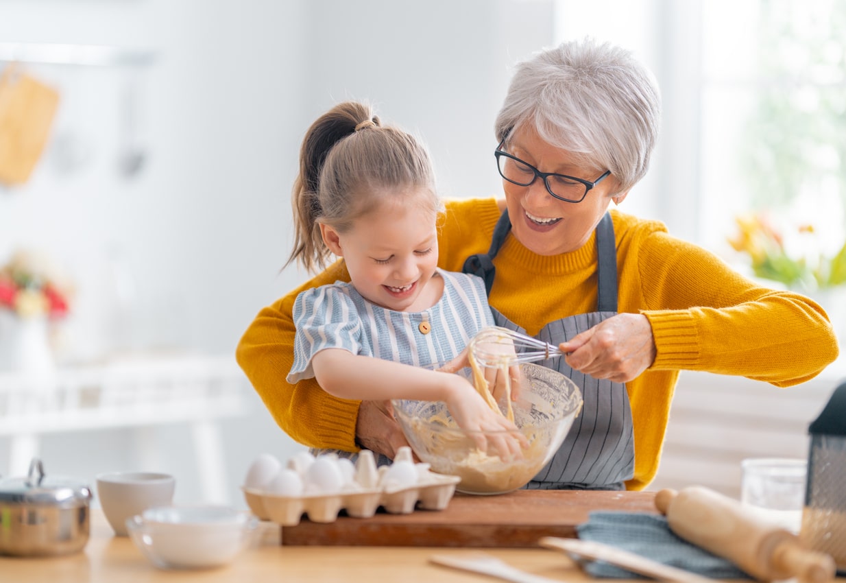 Grandma and granddaughter baking cookies together in the kitchen.
