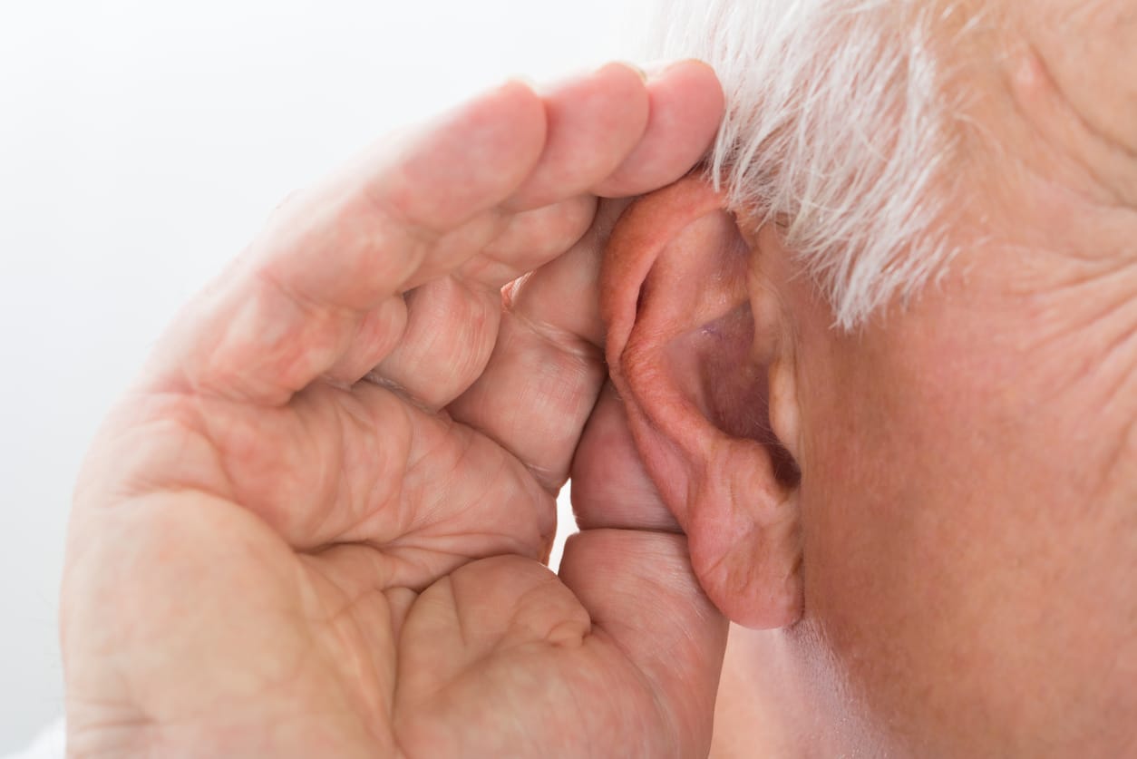 Man holds hand behind ear to indicate he cannot hear