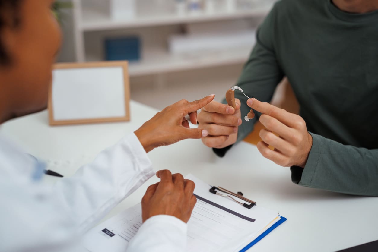 Audiologist teaching a man about his new hearing aid.