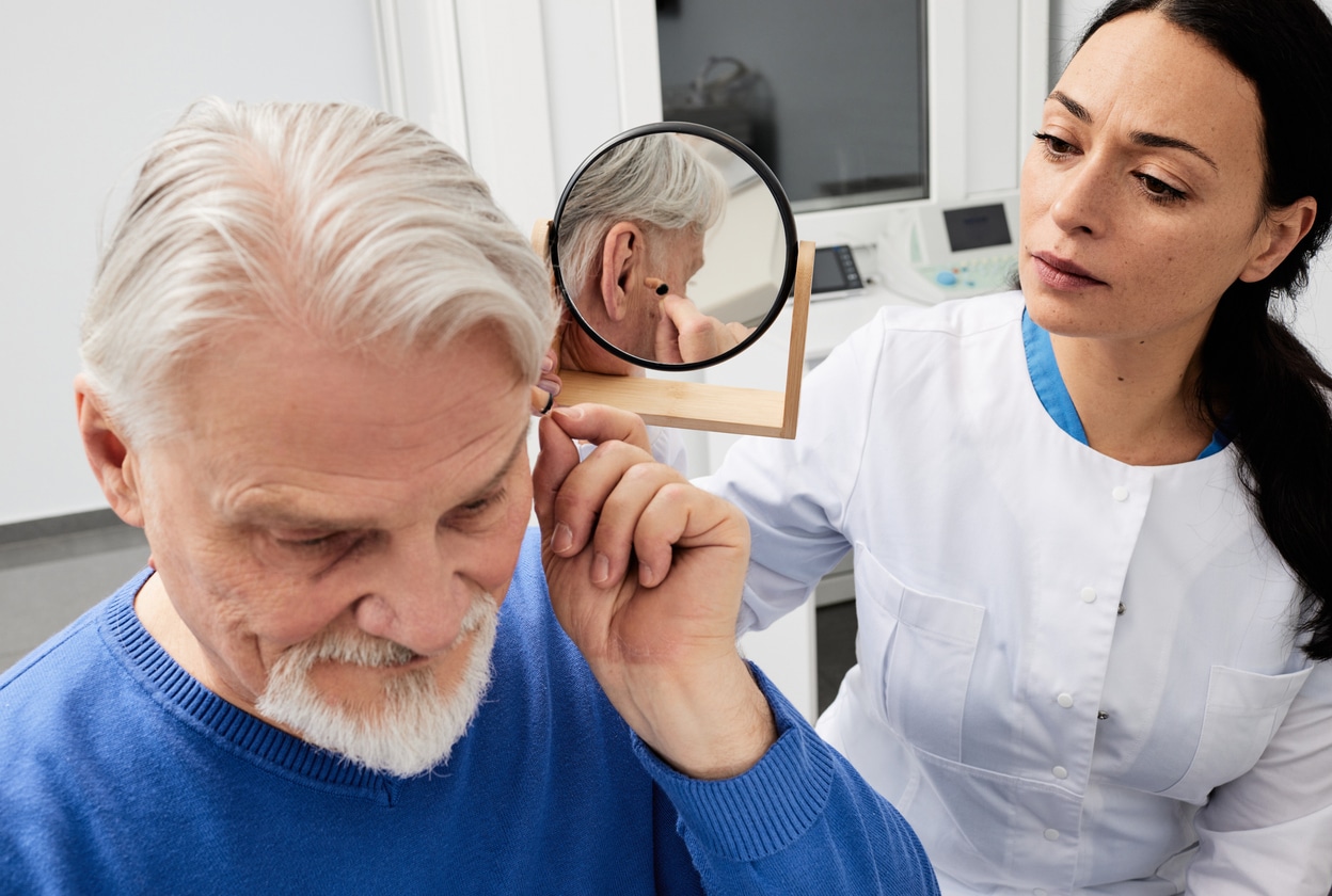 Man places hearing aid in ear