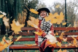 Happy woman sitting on a park bench enjoying the fall